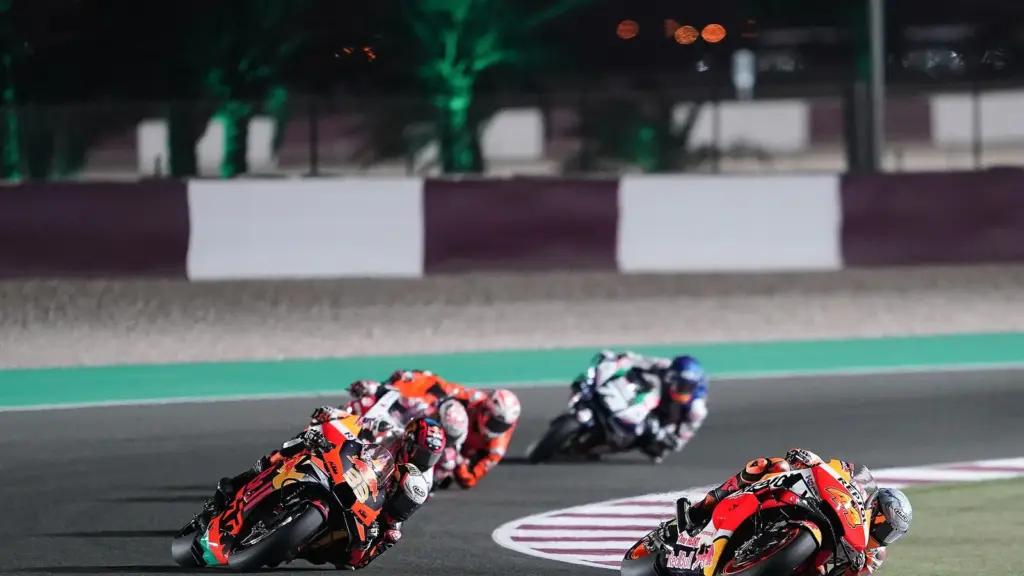 MotoGP riders racing under floodlights at Lusail International Circuit in Qatar
