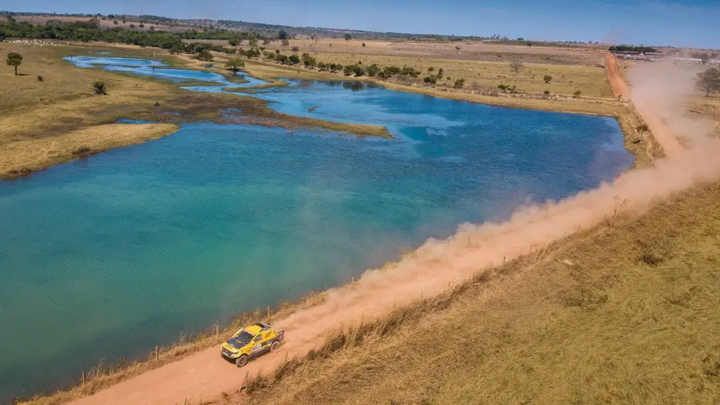 A rally car on a dirt stage beside a lagoon during the 2019 Rally dos Sertões