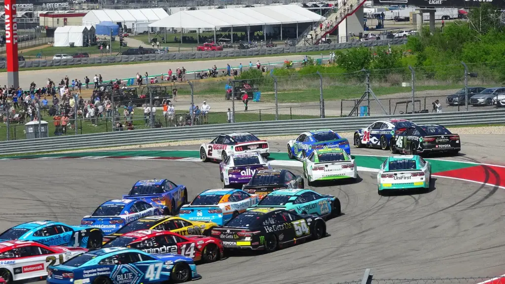 NASCAR Cup cars racing in a tight pack through Turn 1 after a restart at the 2023 race at Circuit of the Americas