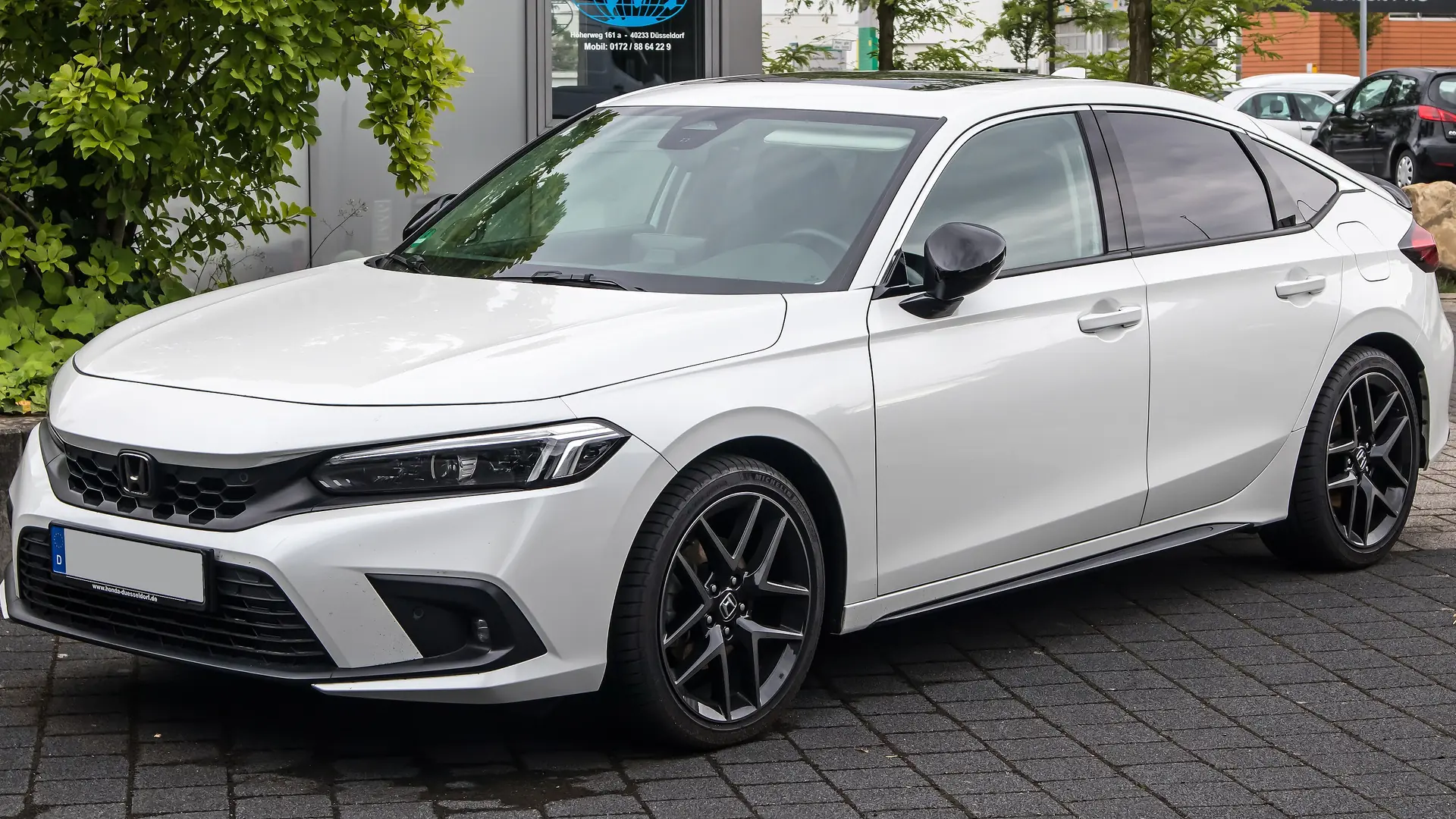 White eleventh-generation Honda Civic e:HEV hybrid hatchback, front three-quarter view