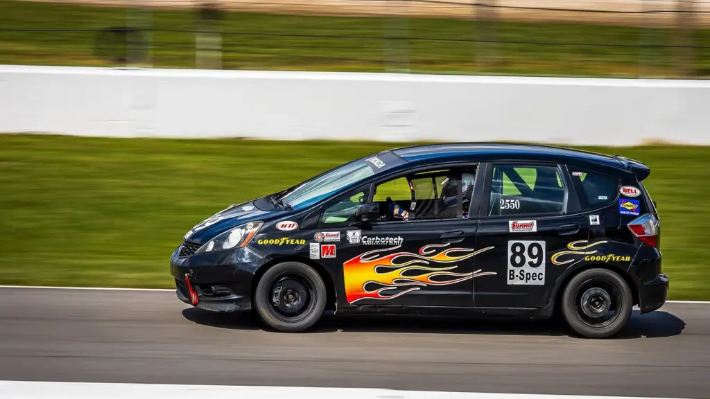 Black Honda Fit B-Spec race car on the front straight at Mid-Ohio