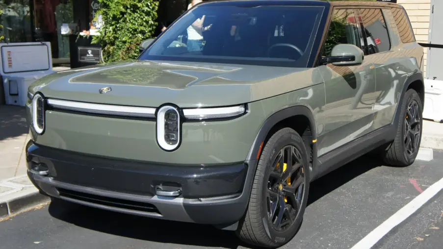 Green Rivian R2 SUV parked outside a Rivian store
