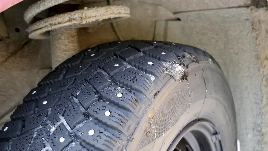 Close-up of a studded winter tire showing the metal studs in the tread