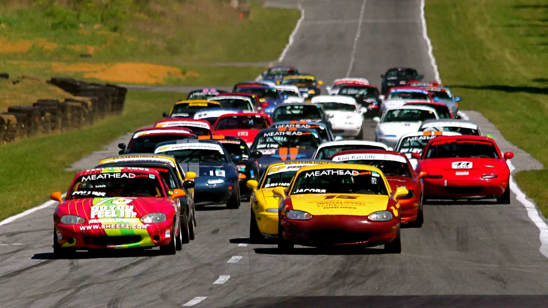 A pack of Spec Miata race cars at the start of an SCCA club race