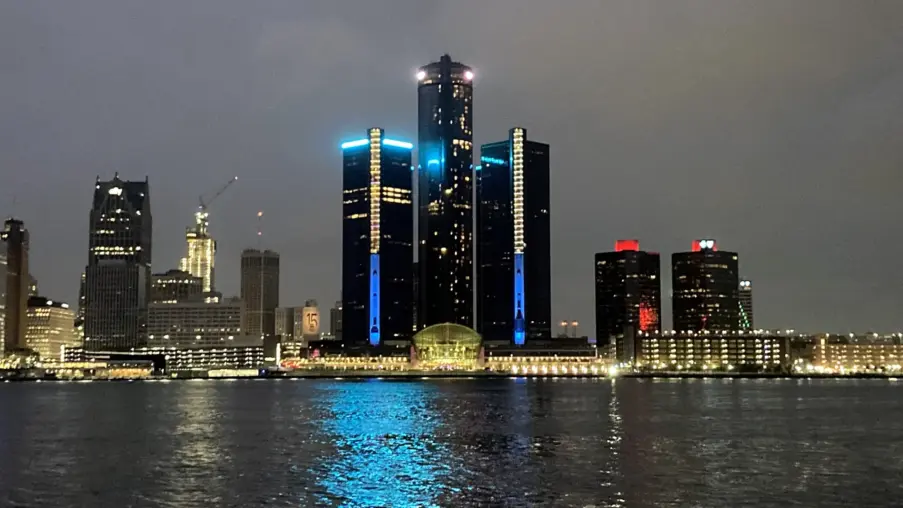 The Detroit skyline and GM Renaissance Center lit up at dusk, seen across the Detroit River from Windsor, Ontario